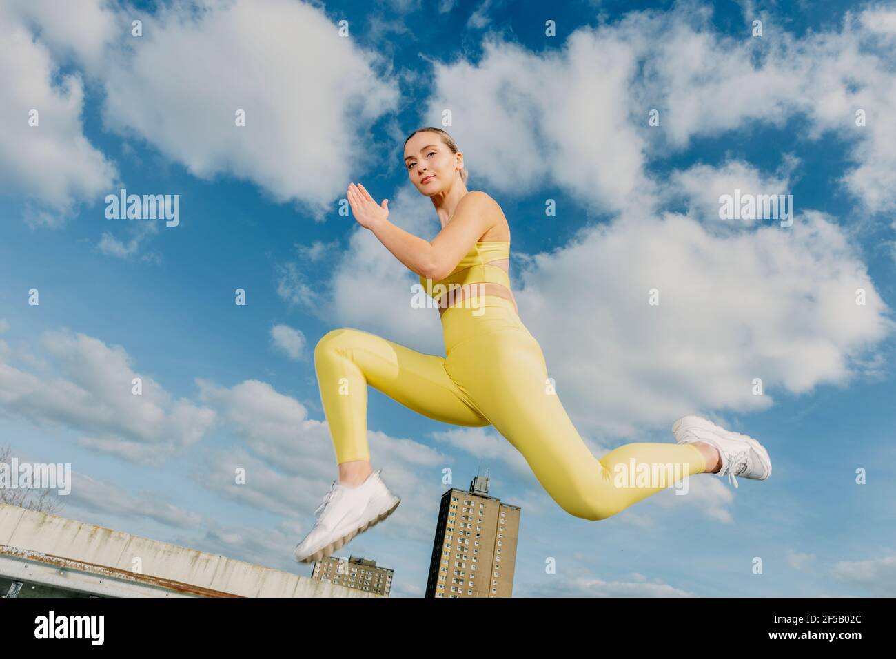 Sportliche Frau in gelber Sportbekleidung in der Luft, springen beim Laufen. Stockfoto