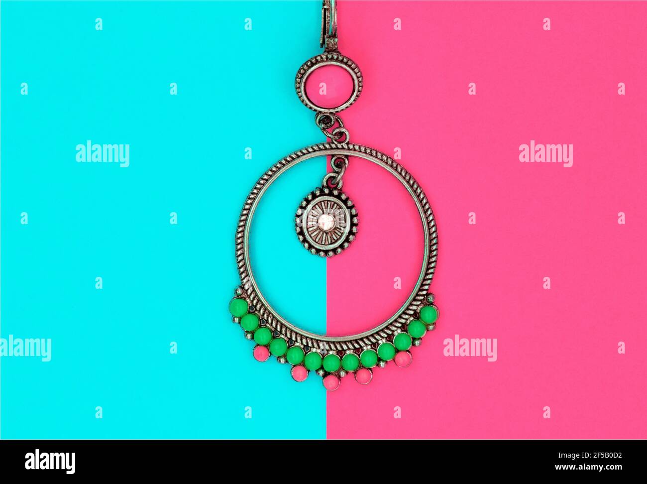 Ethnische Dekorationen auf farbigen Papierblättern. Ohrringe Ringe Amulette Perlen. Türkisrosa Hintergrund Stockfoto