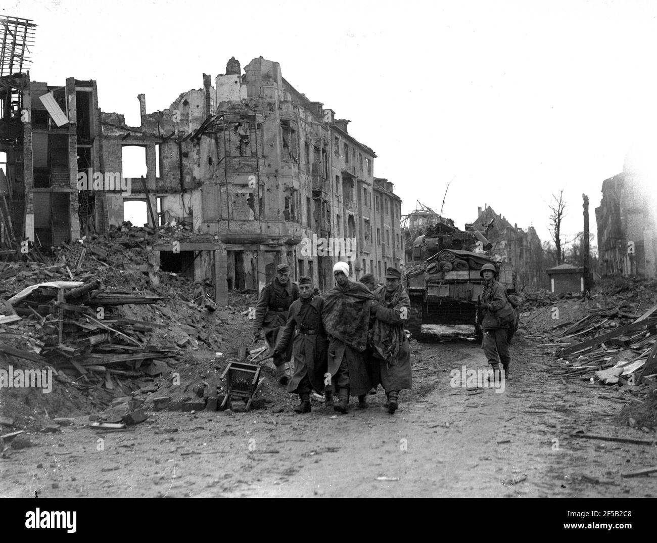 Köln, Deutschland 1945 amerikanische Truppen eskortieren verletzte gefangene deutsche Soldaten, nachdem sie sich während des Zweiten Weltkriegs nach schweren Bombardierungen der Stadt ergeben hatten. Zweiter Weltkrieg. deutsche Niederlage alliierter Sieg Deutschland 1940er Jahre Kapitulation Europa Europäische Geschichte Zerstörung Stockfoto