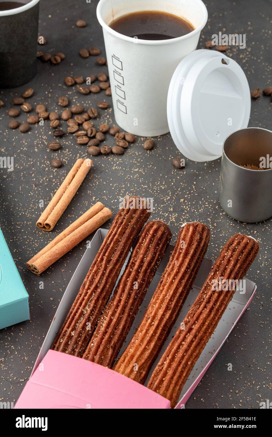 Blick von oben auf Kaffee zum Mitnehmen neben Schokolade gefüllt und einfache Churros. Stockfoto