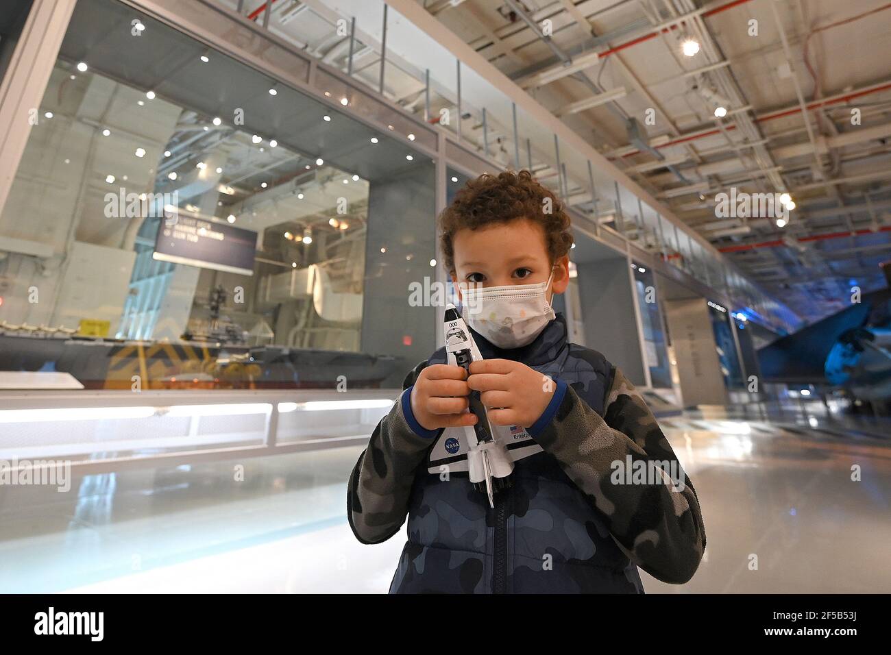 New York, USA. März 2021, 25th. Alessio, 4, zeigt sein neu erworbenes Space Shuttle-Spielzeug, während er und seine Familie das Intrepid Sea, Air & Space Museum besuchen, das heute nach einem Jahr wegen der COVID-19-Pandemie wieder für die Öffentlichkeit zugänglich ist, New York, NY, 25. März 2021. Das schwimmende Museum, das an Manhattans West Side angedockt ist, wird die Kapazität auf 25% begrenzen, den Eintritt zeitlich eingrenzen und Gesichtsbedeckung und soziale Distanzierung erfordern. (Foto von Anthony Behar/Sipa USA) Quelle: SIPA USA/Alamy Live News Stockfoto