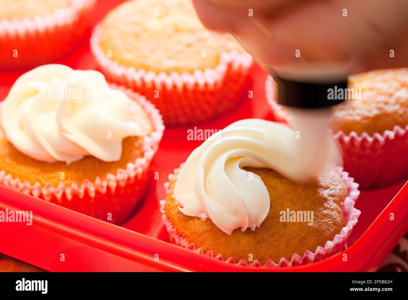 Weiße Zuckerguss auf hausgemachte Cupcakes auftragen Stockfoto