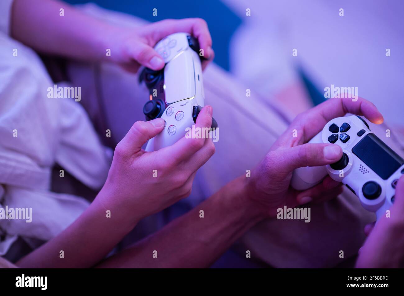 Lächelndes Paar hält Gamepads spielen Videospiel zu Hause. Low-Angle-Aufnahme junger Menschen, die während der Selbstisolation gegen Pandemie Zeit miteinander verbringen Stockfoto