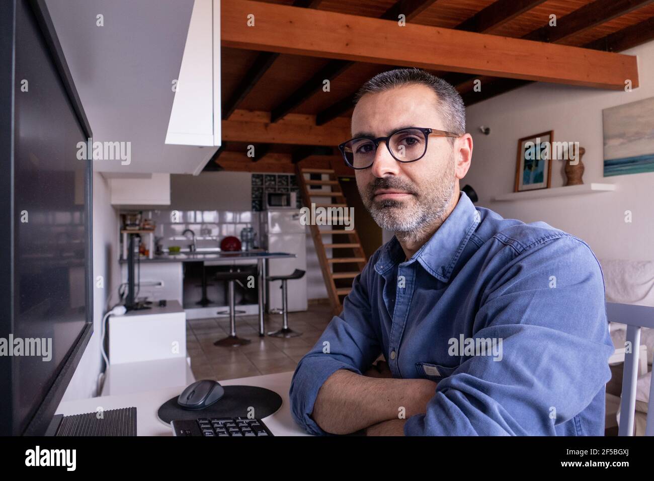 Kaukasischer spanischer Mann Portrait sitzt im Homeoffice. 42 Jahre alter Rüde mit Bart und Brille Stockfoto