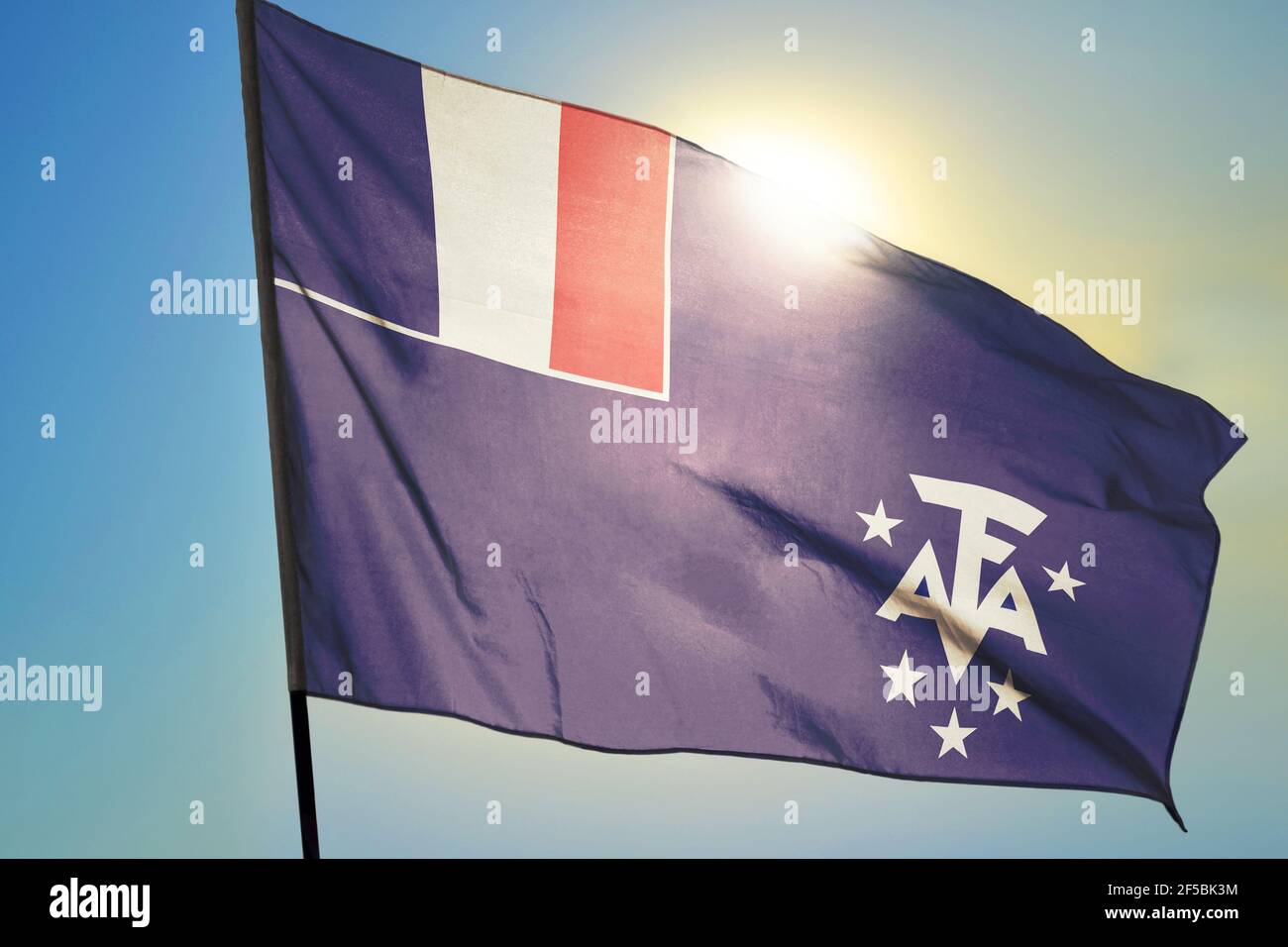 Französische Süd- und Antarktisflagge winkt dem Wind Vor der Sonne Stockfoto