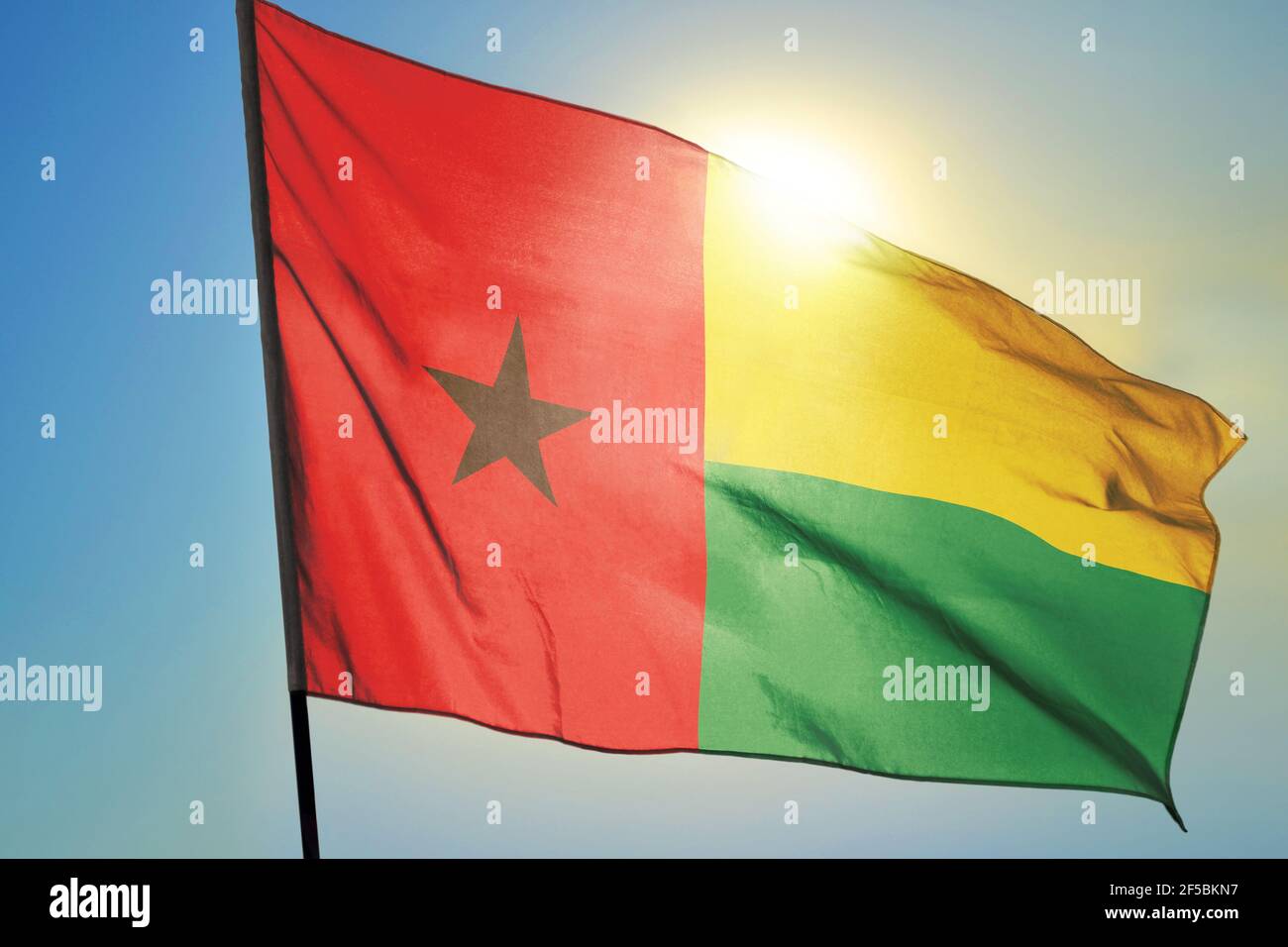 Guinea-Bissau Flagge winkt auf dem Wind vor der Sonne Stockfoto