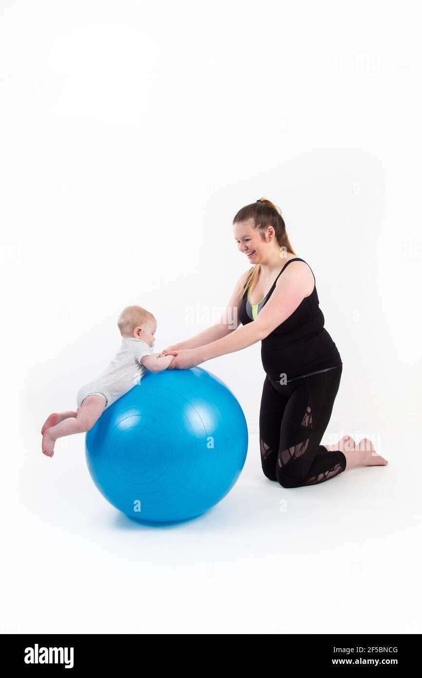 Mutter mit Baby aufgehängt hält seinen Kopf auf einem Gymnastikball Stockfoto