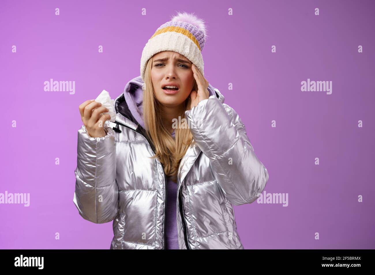 Ill verärgert schluchzend niedlich blonde Mädchen fühlen sich unwohl halten Serviette Gewebe berühren Kopf Tempel Stirnrunzeln Grimacing schmerzhafte Migräne wurde krank Im Winter Stockfoto