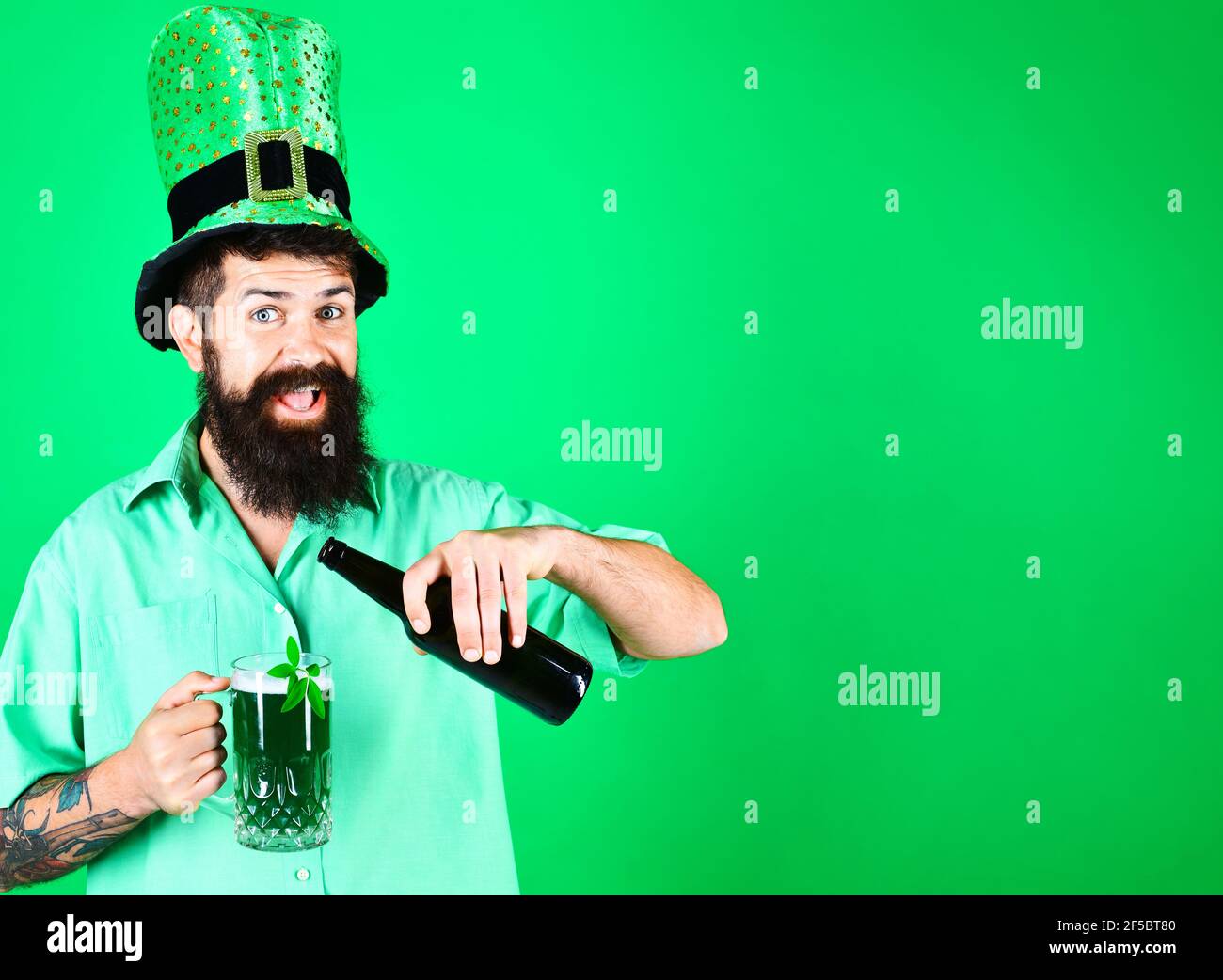 St. Patricks Day. Lächelnder bärtiger Mann in Koboldhut gießt Bier in Glas. Stockfoto