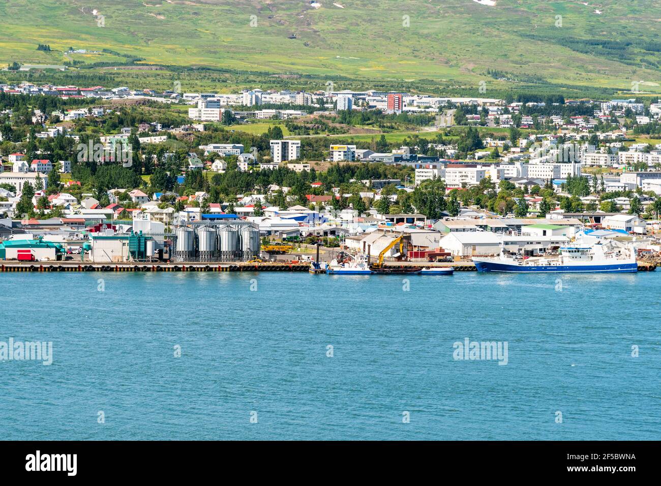 Hafen und Industriepark an einem Fjord an einem sonnigen Frühlingstag. Wohngebäude am Hang sind im Hintergrund. Stockfoto