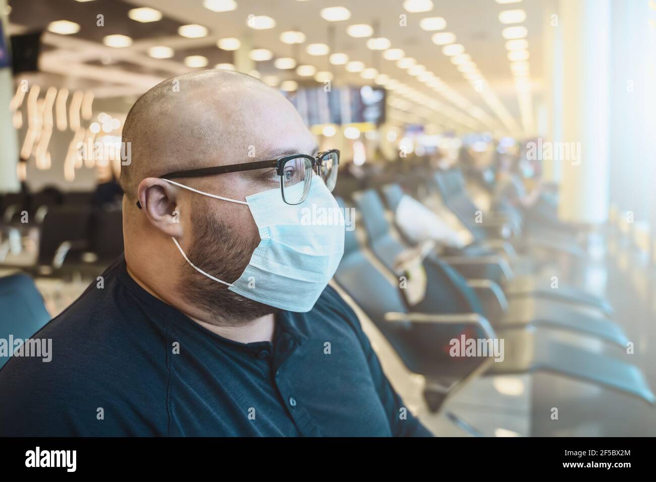 Mann in Brille in Schutzmaske wartet auf Bord am Terminal Flughafen Stuhl. Flugzeugtransport durch Arbeit oder Reise in covid-19 Pandemie Zeiten. Stockfoto