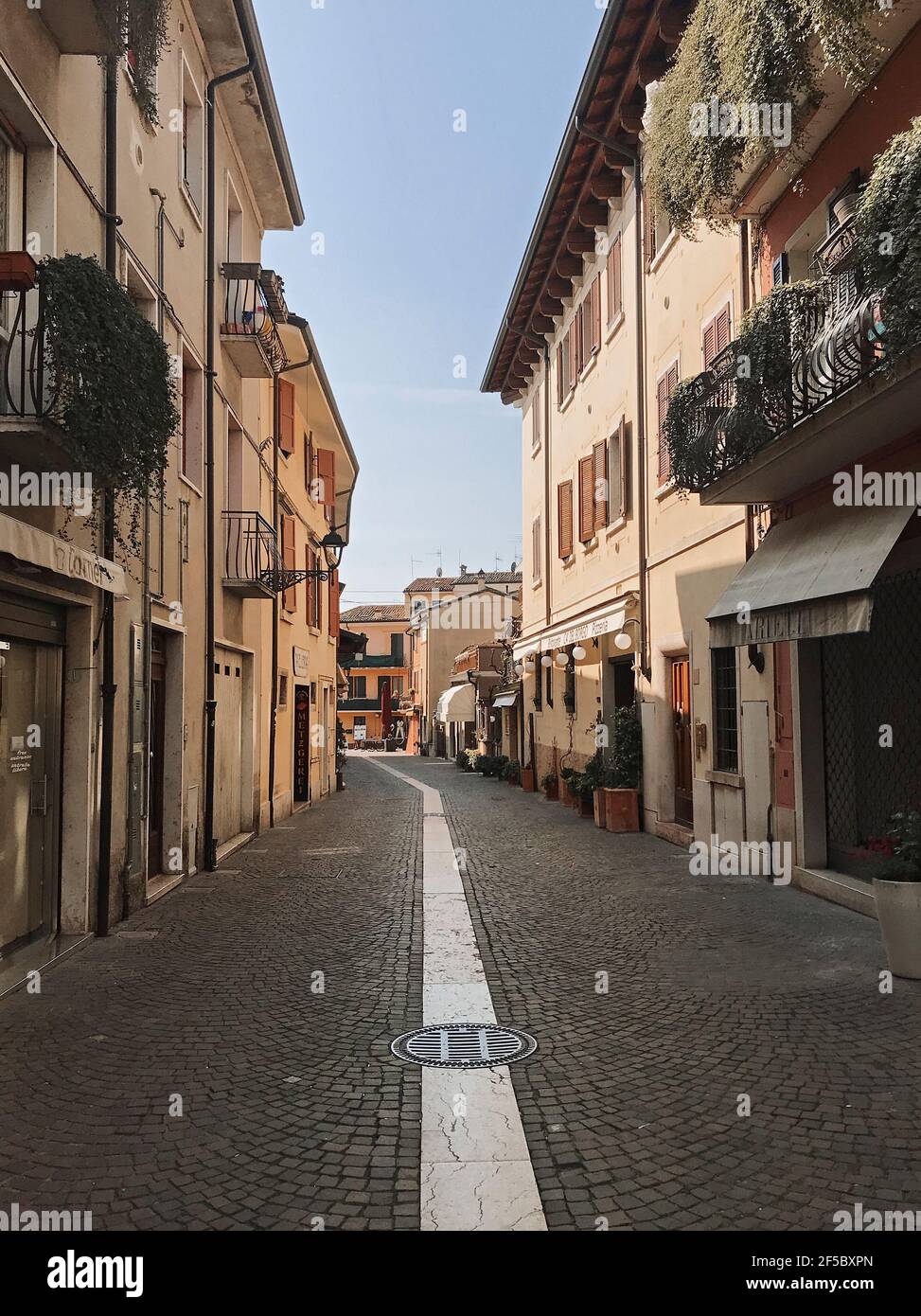 Bardolino, Italien. März 2021, 25th. Der fünfte Tag des Frühlings, zusammen mit Via BG.Giuseppe Garibaldi Zentrum in Bardolino Stadt, am Mittag (11,41CET). Jedes Jahr kamen im Frühjahr tausend Touristen in die Stadt am Gardasee. Heute sind die Straßen Wüste, Einzelhandel, Bar, Restaurants während der dritten Welle der Covid-19-Epidemie geschlossen, in Bardolino, Italien, 25. März 2021. Quelle: ALEJANDRO SALA/Alamy Live News Stockfoto