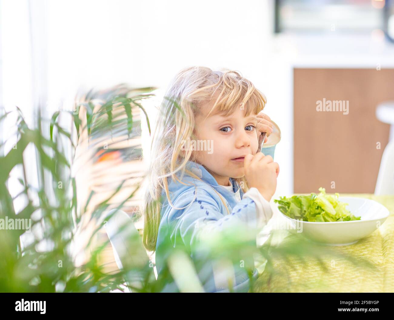 Kleines blondes Mädchen, das sich weigert, Gemüsesalat zu essen. Lifestyle-Konzept Stockfoto
