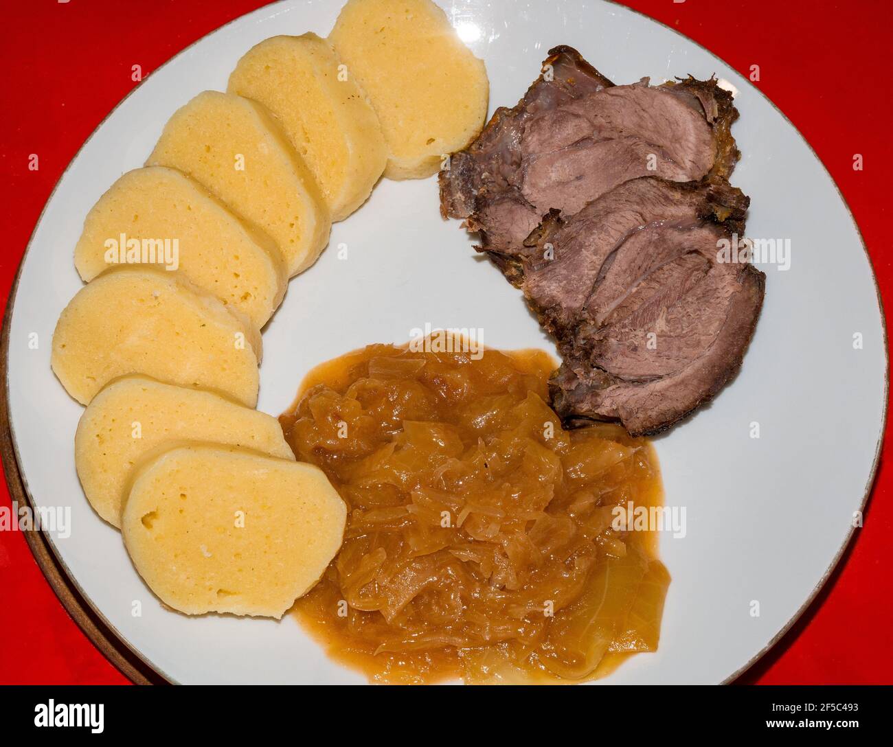 Geröstetes Wildschweinfleisch mit Kartoffelknödeln und Süß- und Sauerkraut. Stockfoto