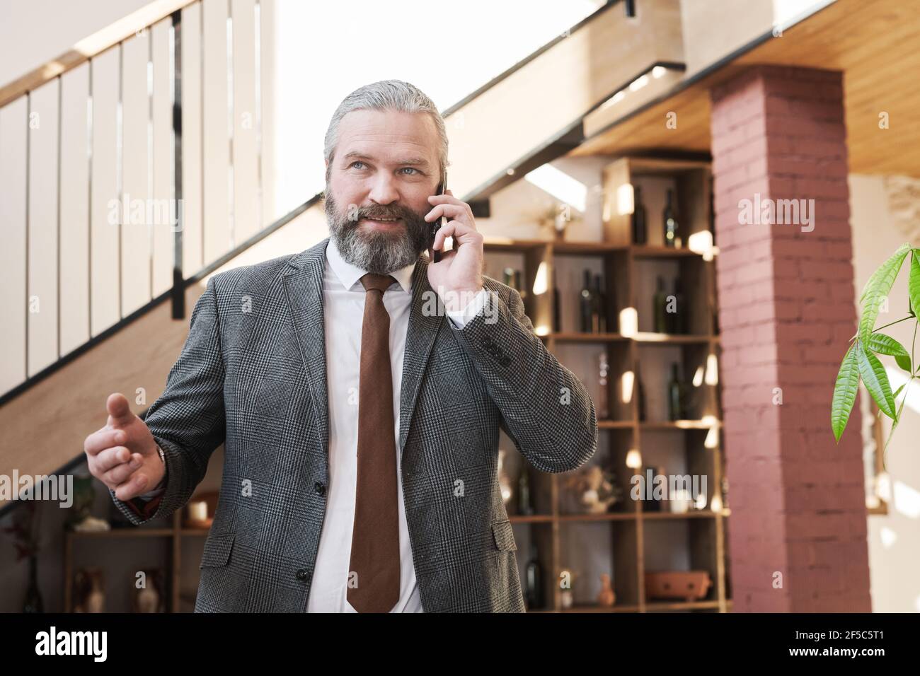 Selbstbewusst reifen Geschäftsmann mit einem Gespräch auf Handy, während Zum Meeting im Restaurant gehen Stockfoto