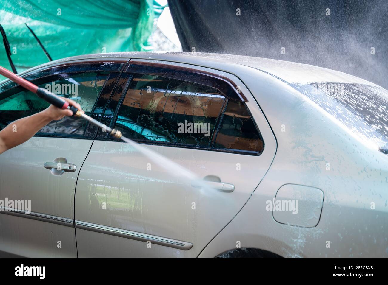 Nahaufnahme eines Mannes Hände wäscht sein Auto mit einem großen Kopf Wasser von einem karcher auf Open Air. Reinigung und Desinfektion. Autowaschservice concep Stockfoto