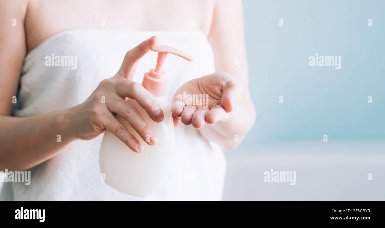 Weibliche Hände Pumpen aus Creme, Lotion, Flüssigseife aus einer weißen Flasche, selektive Fokus. Konzept der Hautpflege. Hygiene einer erwachsenen Frau Stockfoto