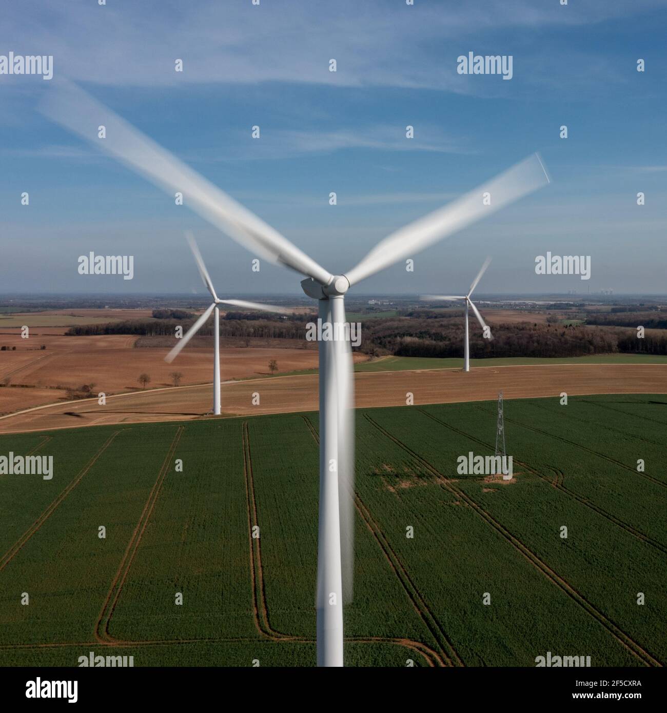 Luftaufnahme eines Windparks über grünem Ackerland mit großen weißen Turbinen, die während einer Energiekrise grünen Strom aus erneuerbaren Quellen erzeugen Stockfoto