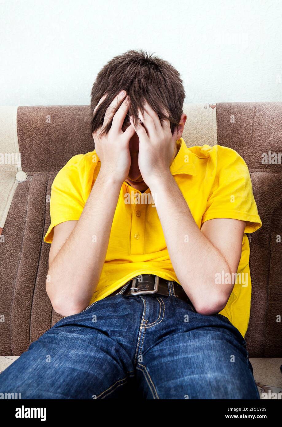 Trauriger junger Mann auf der Couch im Zimmer Stockfoto