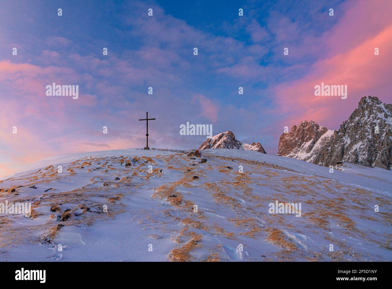 Bergkreuz auf einem schneebedeckten Gipfel während des Übergangs zwischen der goldenen und blauen Stunde bei Sonnenuntergang. Sulzenschneid, Filzmoos, Salzburg Stockfoto