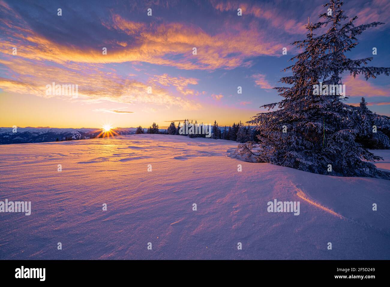 An einem kalten Wintertag geht die bunte Sonne auf dem Rossbrand zwischen Radstadt und Filzmoos in Salzburg, Österreich, unter. Stockfoto