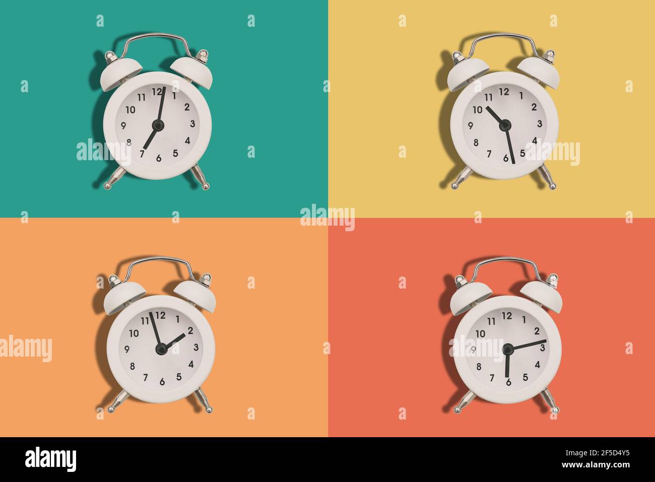 Vier Wecker auf farbigem Hintergrund. Die Zeiger der Uhr zeigen unterschiedliche Zeiten an. Flach liegend. Stockfoto