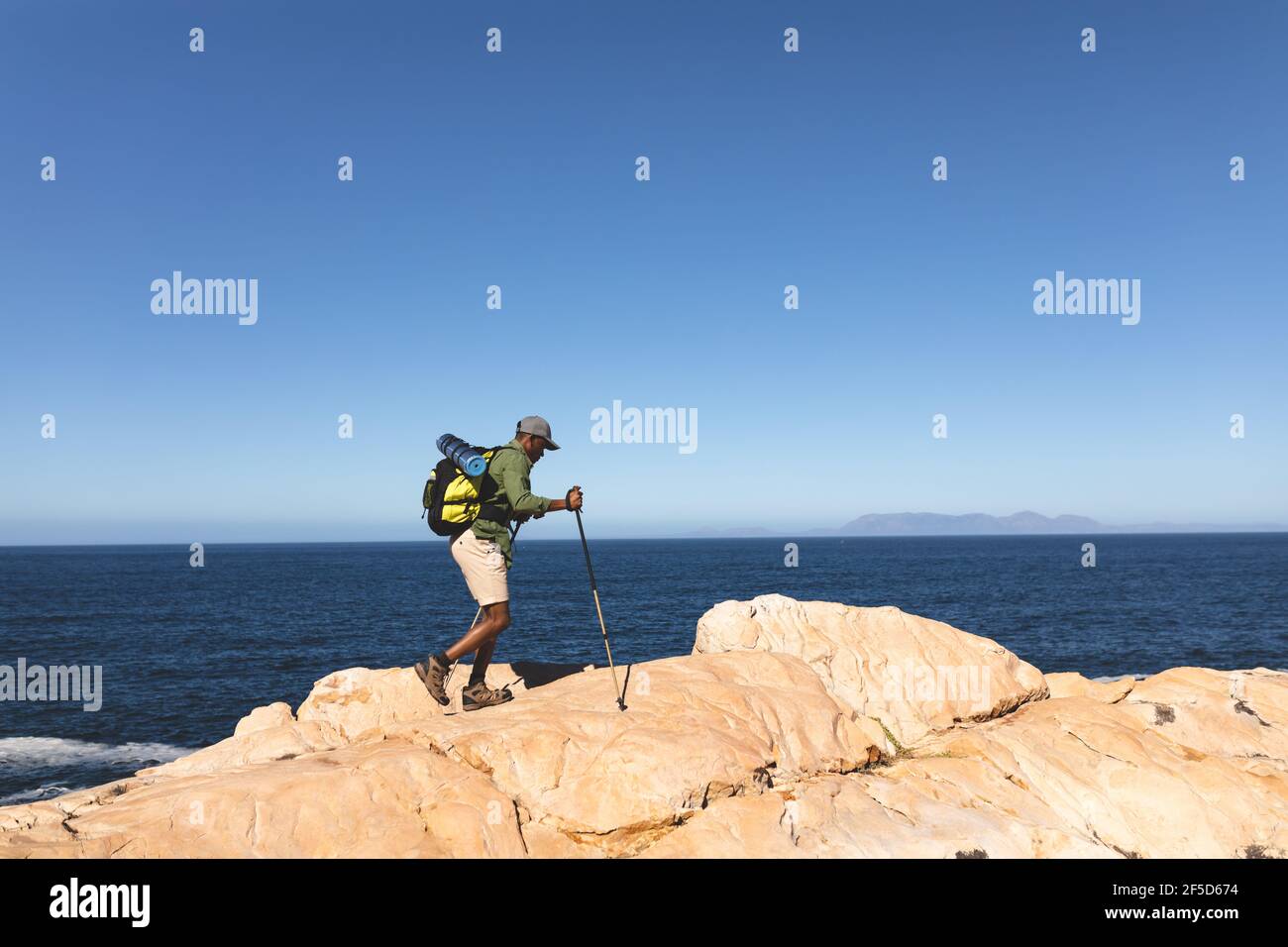 Afroamerikanischer Mann, der im Freien mit Wanderstöcken unterwegs ist Landschaft auf einem Berg Stockfoto