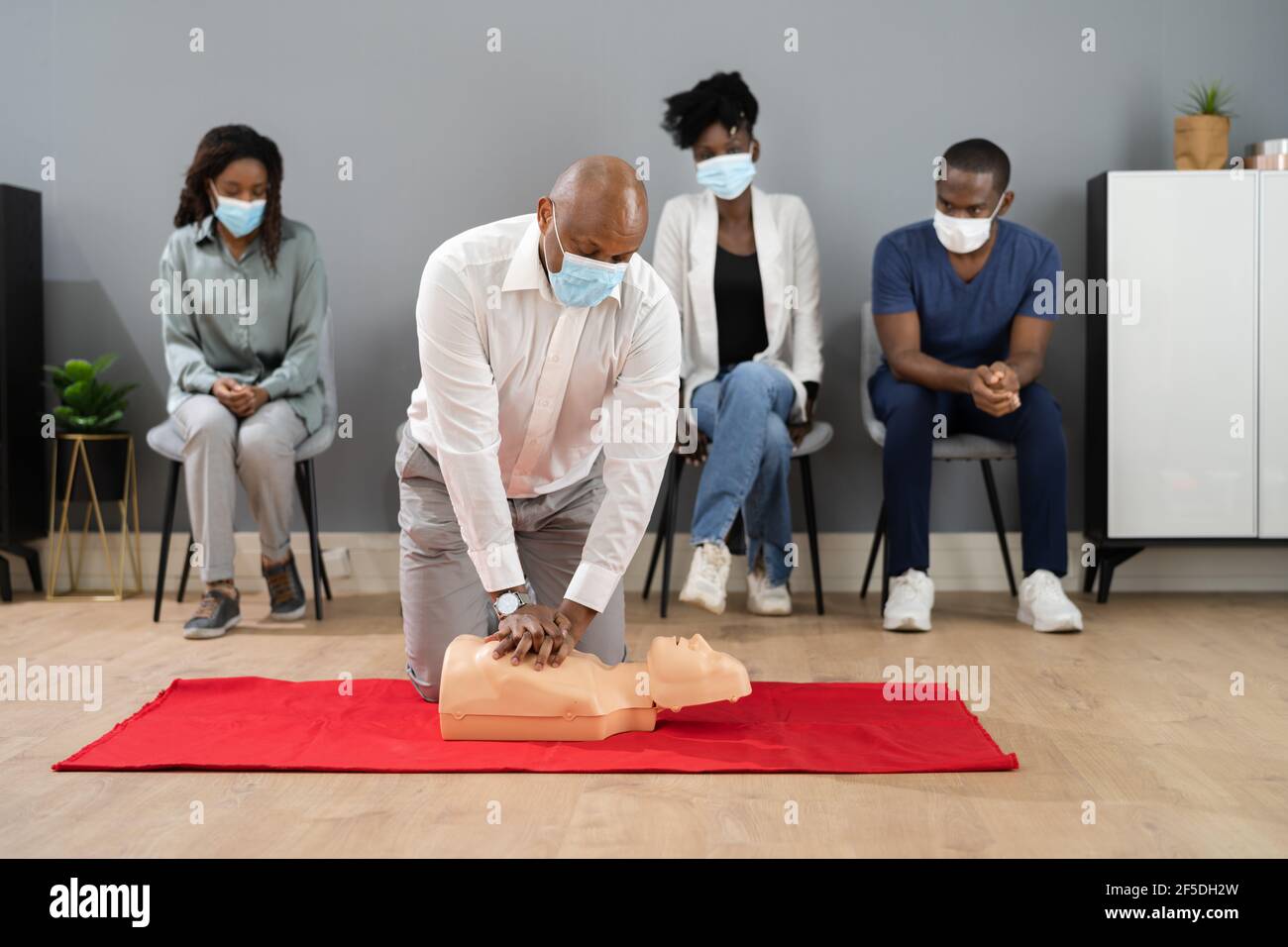 Erste-Hilfe-CPR-Training mit einem Sanitäter in Gesichtsmaske Stockfoto