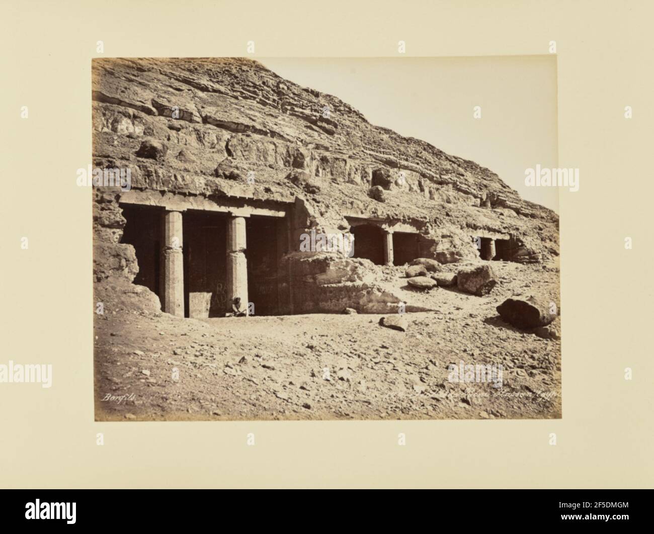Grotte de Béni-Hassan, Égypte. Blick auf die Eingänge zu einer Felsstruktur, unterstützt von proto-dorischen Säulen. Ein Einheimischer sitzt an der Basis einer der Säulen. (Recto, Print) Rechts unten, im Negativ eingeschrieben: '122. Grotte de BÈni-Hassan Schrägstrich …Gypte teilweise beschnitten'; Stockfoto