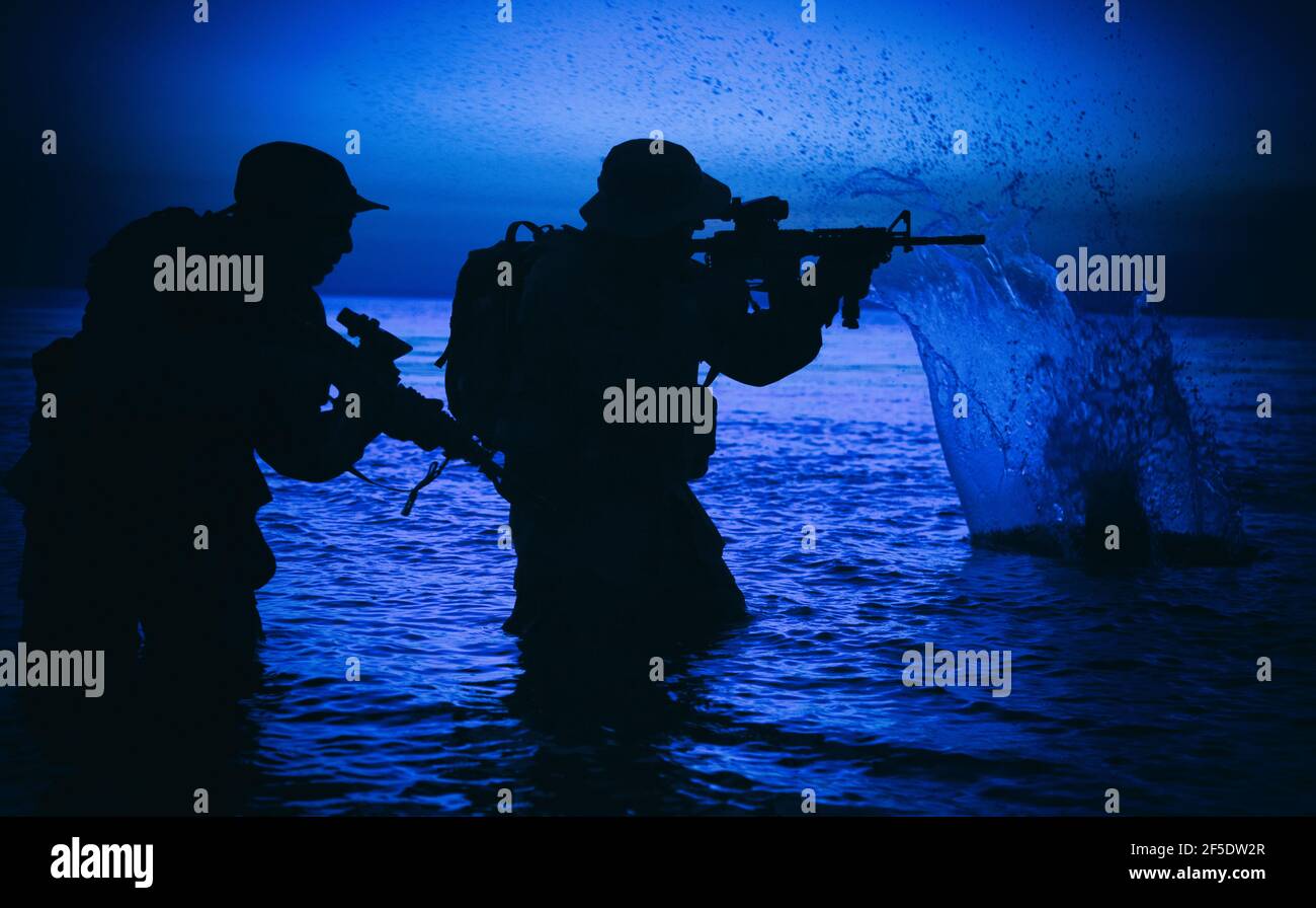 Armee Soldaten Team, spezielle Einsatzkräfte Infanteristen Landung auf See, zielen und schießen mit Service-Gewehr während des Brands an Land am Abend oder am Morgen Zeit. Militärische amphibische Operation Stockfoto