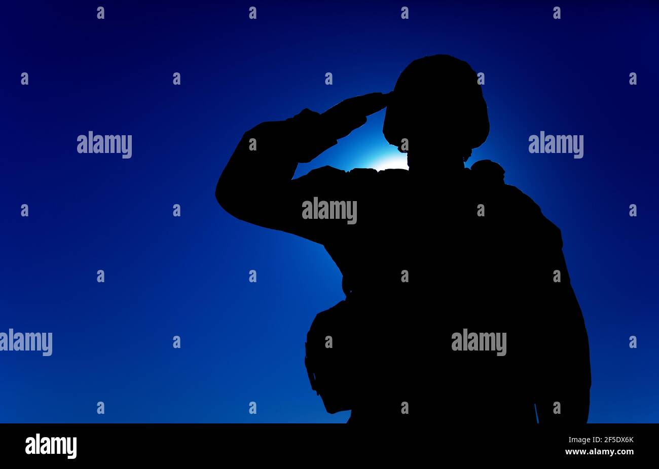 Die Silhouette des Soldaten im Kampfhelm und die Munition, die auf dem Hintergrund des Sonnenuntergangs grüßen. Armee Spezialeinheiten Kämpfer, Marines Rifleman zeigt Respekt, Begrüßung Offizier mit Gruß Geste Stockfoto