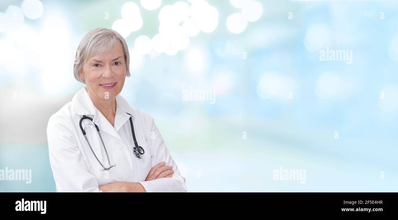 Porträt eines freundlichen lächelnden reifen Arztes, verschwommener blauer Hintergrund, Text- oder Textraum. Stockfoto