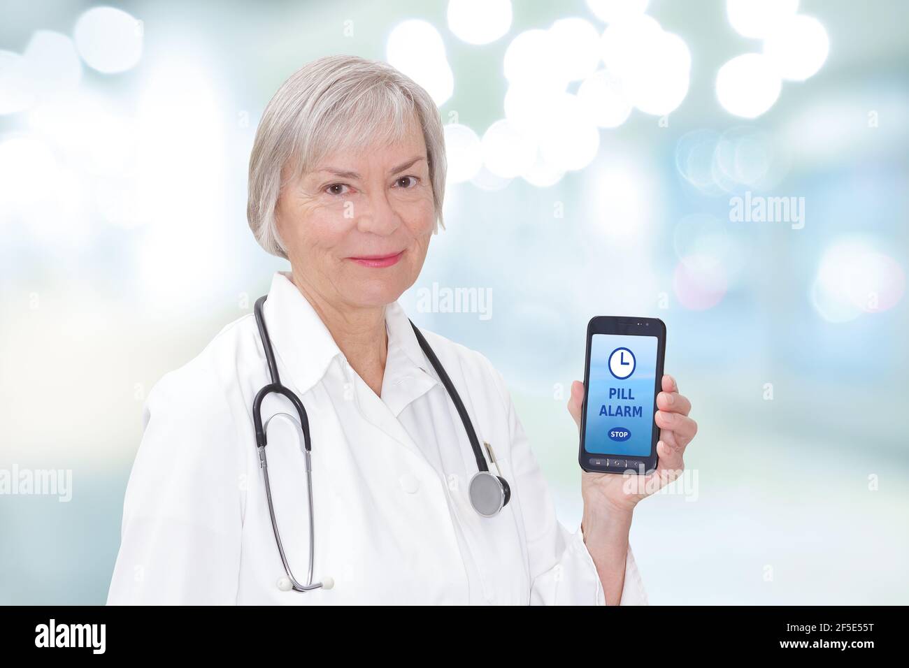 Freundliche Oberarzt hält ein Handy oder Handy mit einer Pille Alarm App. Stockfoto