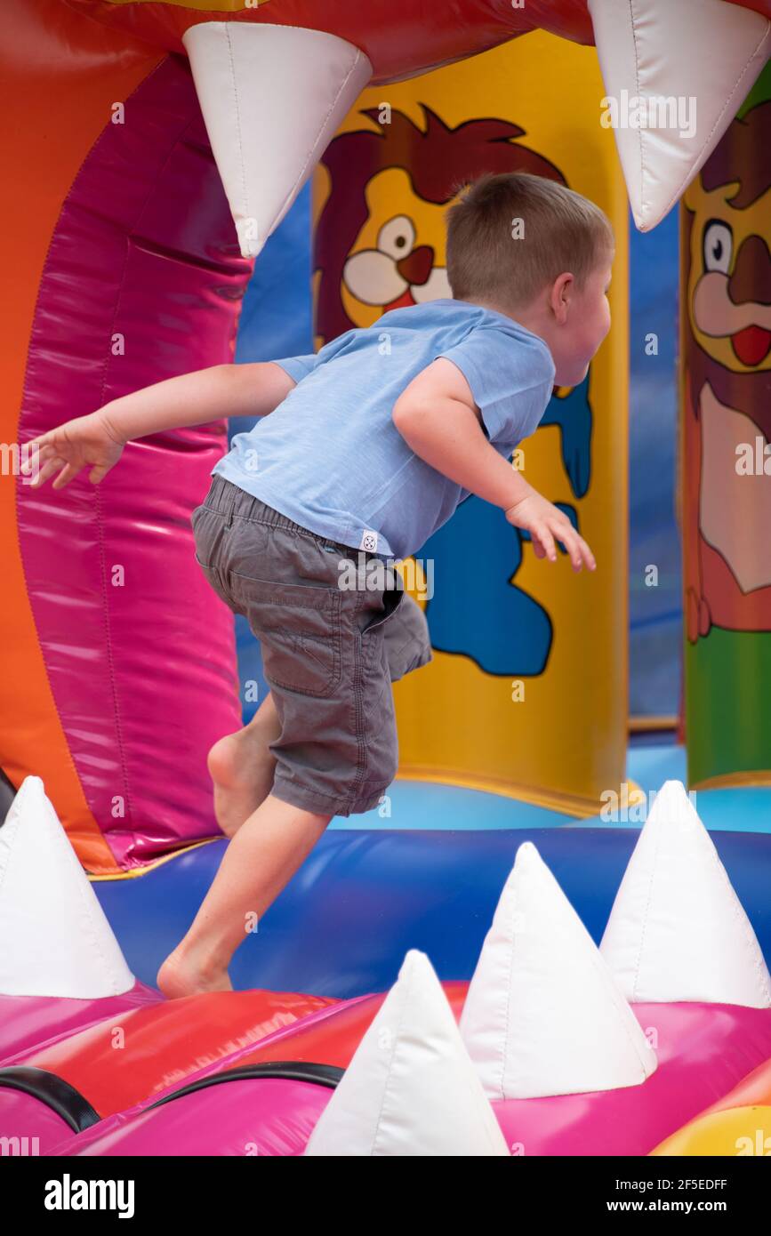 Ein kleiner Junge, der sich auf einer aufblasbaren Hüpfburg amüsieren kann Stockfoto