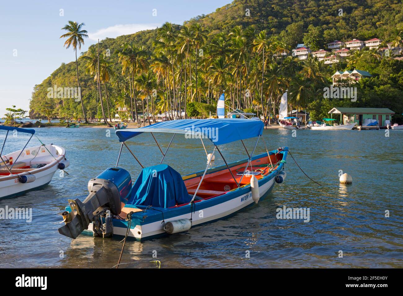 Marigot Bay, Castries, St. Lucia. Buntes Wassertaxi, das am Ufer festgemacht ist, Labas Beach im Hintergrund. Stockfoto
