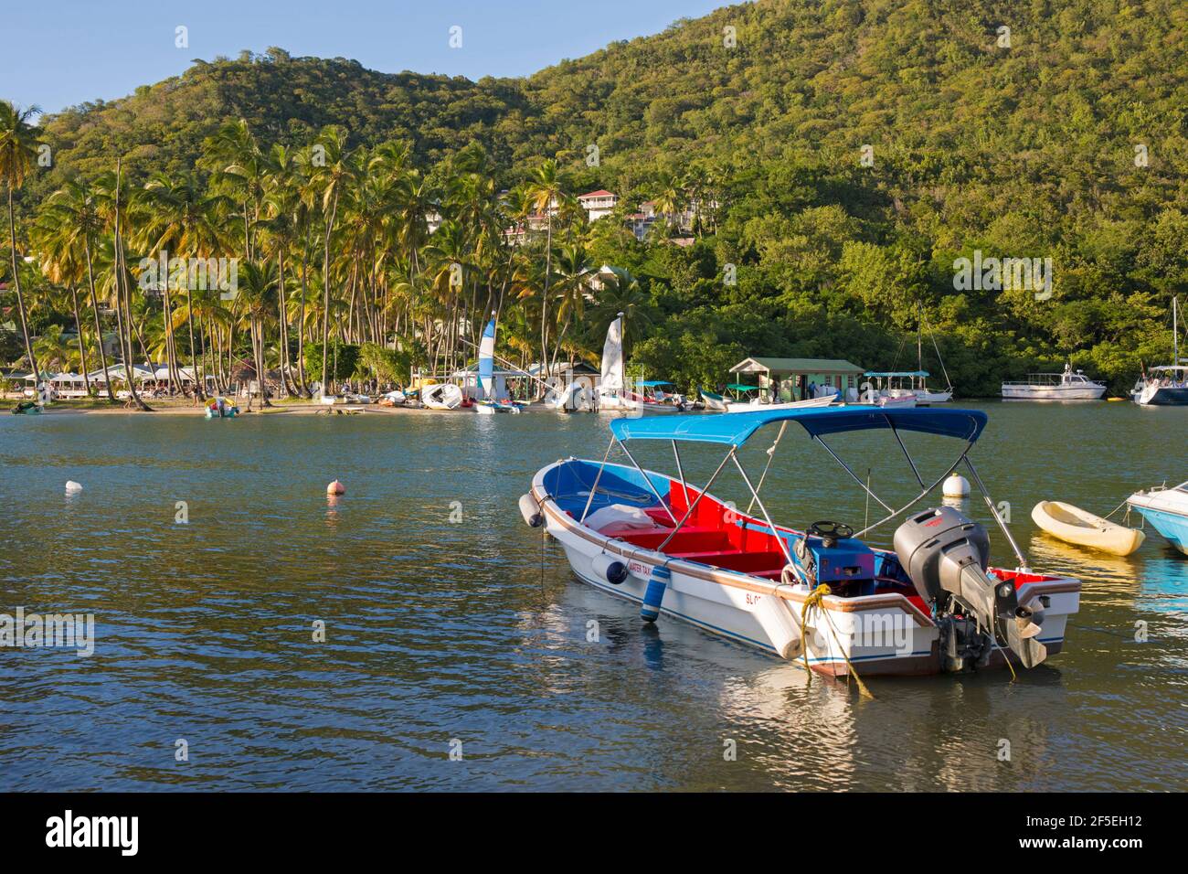 Marigot Bay, Castries, St. Lucia. Buntes Wassertaxi, das am Ufer festgemacht ist, Labas Beach im Hintergrund. Stockfoto