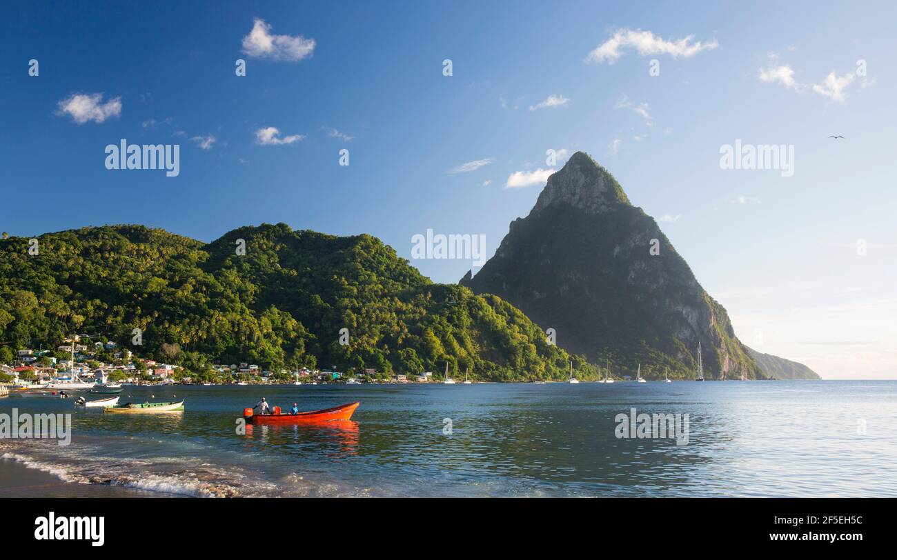 Soufriere, St. Lucia. Blick vom Sandstrand über die Soufriere Bay nach Petit Piton, abends Fischer im farbenfrohen Boot am Ufer. Stockfoto