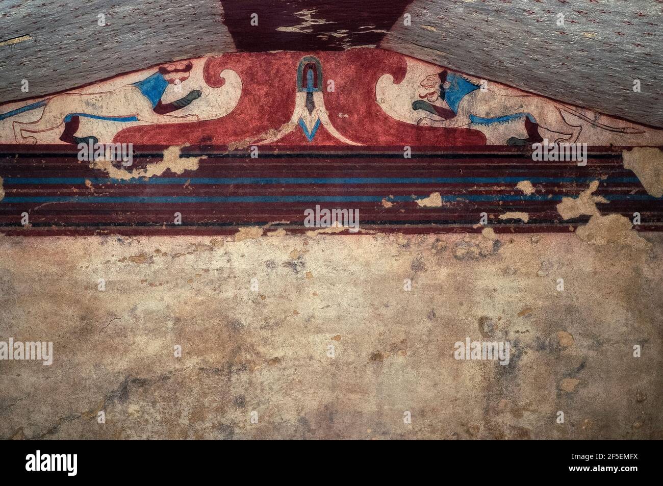 Zwei große Katzen, ein Panther (links) und ein Löwe (rechts), beide in unnatürlichem hellblau gefärbt, stehen auf beiden Seiten eines zentralen Trägers und einer umgekehrten Lotusblüte unter dem Dach des Grabes der Lotusblume in der Monterozzi-Nekropole der antiken etruskischen Tarchuna oder Tarchna. Die 1962 entdeckte Kammer stammt aus der Zeit um 520 v. Chr. und gehört zu den 200 Gräbern der Adligen oder Adligen des Stadtstaates, die mit Fresken geschmückt werden. Einige andere bemalte Gräber zeigen das alltägliche etruskische Leben, einschließlich Bankette mit Musik und Tanz, Jagd, Leichtathletik und Beerdigungsrituale. Stockfoto