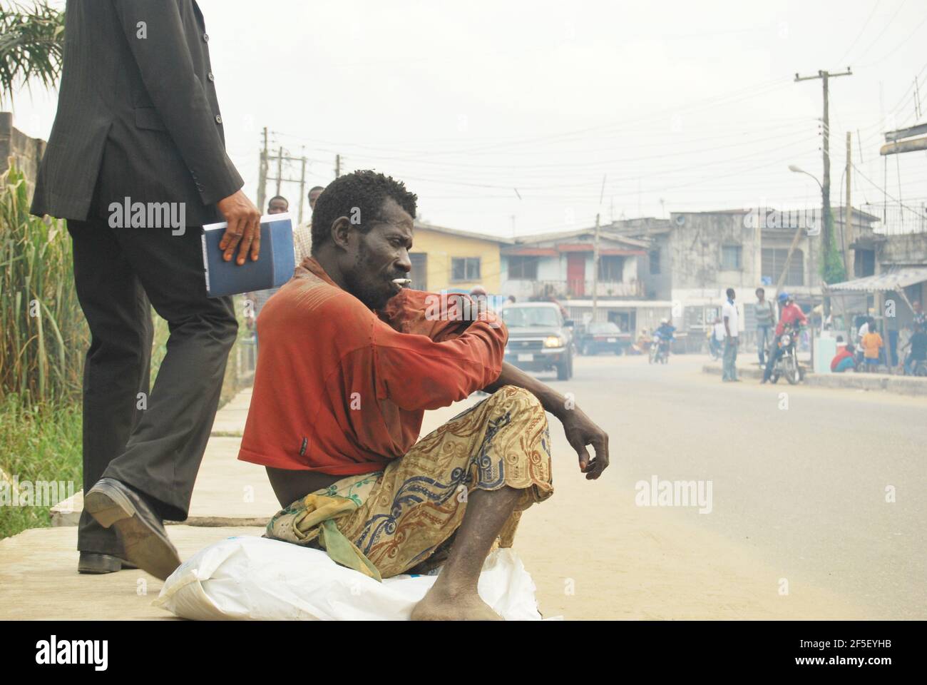 36. Lagos Metro: Psychisch verärgerter Mann, der Zigaretten raucht, entlang der Lagos Road, Nigeria. Stockfoto