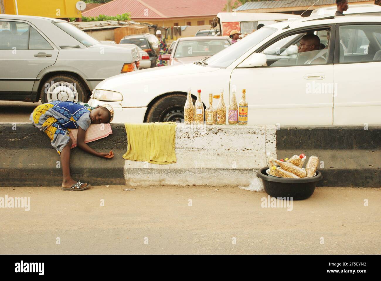 31. Lagos Metro: Erdnussverkäufer schläft auf der Straßenabgrenzung in Lagos, Nigeria. Stockfoto