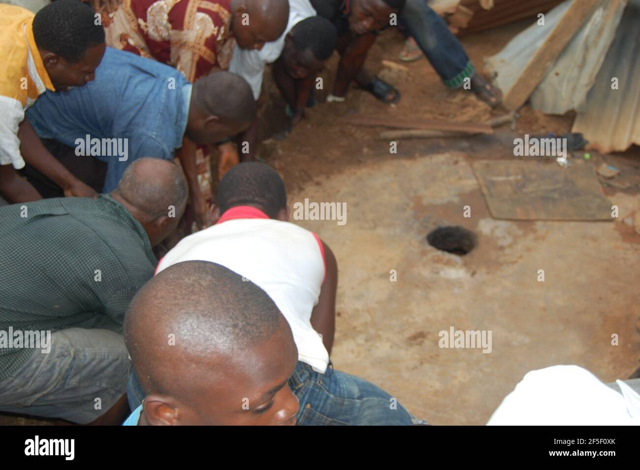 1. Verlassenes Baby: Jugendliche in der Gemeinschaft entfernen die Betonplatte von der Grubentoilette, um das neugeborene Baby, Lagos, Nigeria, zu retten. Stockfoto