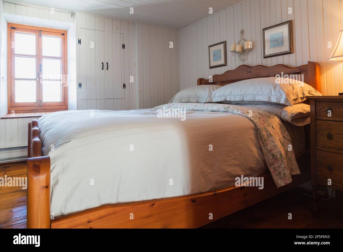 Queen-Size-Bett mit Massivholz-Rahmen, Kopfteil. Fußbrett im Obergeschoss Hauptschlafzimmer mit weiß lackierten schmalen Holzplanken Wände im alten Haus Stockfoto