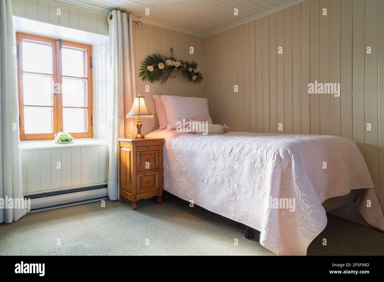 Einzelbett und Nachttisch aus Kiefernholz im Gästeschlafzimmer mit Grüner Teppich im oberen Stockwerk in einem alten Cottage aus dem Jahr 1807 Haus im Stil Stockfoto