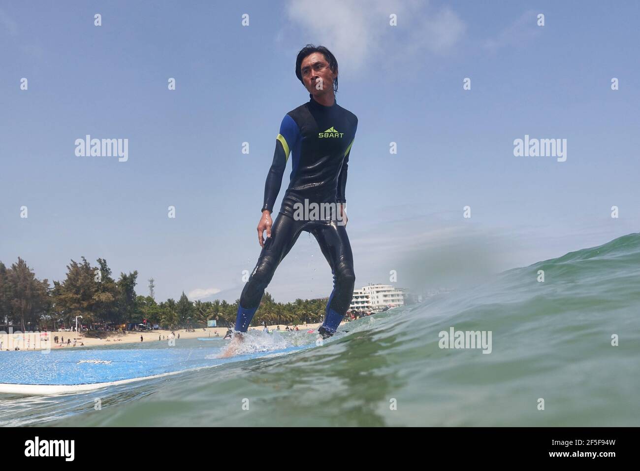 (210326) -- SANYA, 26. März 2021 (Xinhua) -- Foto vom 27. Februar 2021 zeigt Yang Xingfu beim Surfen im Dorf Tenghai in Sanya, südchinesische Provinz Hainan. Das Dorf Tenghai, einst ein kleines Fischerdorf, ist seit dem Surfboom in China ein berühmtes Surfcamp geworden, nachdem es offiziell für das Programm der Olympischen Spiele 2020 in Tokio zugelassen wurde. Das Dorf liegt in Sanya, der südchinesischen Provinz Hainan, und gewann auch Anerkennung für seine großartige Kombination aus Wassersport und Tourismusindustrie.Yang Xingfu, ein örtlicher Dorfbewohner, ist einer der frühesten Surfer in Tenghai. Yang verlobt sich einmal Stockfoto