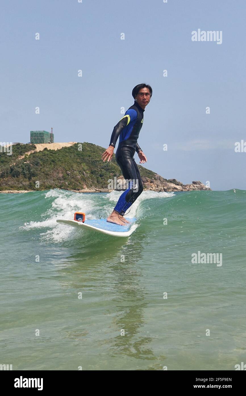 (210326) -- SANYA, 26. März 2021 (Xinhua) -- Foto vom 27. Februar 2021 zeigt Yang Xingfu beim Surfen im Dorf Tenghai in Sanya, südchinesische Provinz Hainan. Das Dorf Tenghai, einst ein kleines Fischerdorf, ist seit dem Surfboom in China ein berühmtes Surfcamp geworden, nachdem es offiziell für das Programm der Olympischen Spiele 2020 in Tokio zugelassen wurde. Das Dorf liegt in Sanya, der südchinesischen Provinz Hainan, und gewann auch Anerkennung für seine großartige Kombination aus Wassersport und Tourismusindustrie.Yang Xingfu, ein örtlicher Dorfbewohner, ist einer der frühesten Surfer in Tenghai. Yang verlobt sich einmal Stockfoto