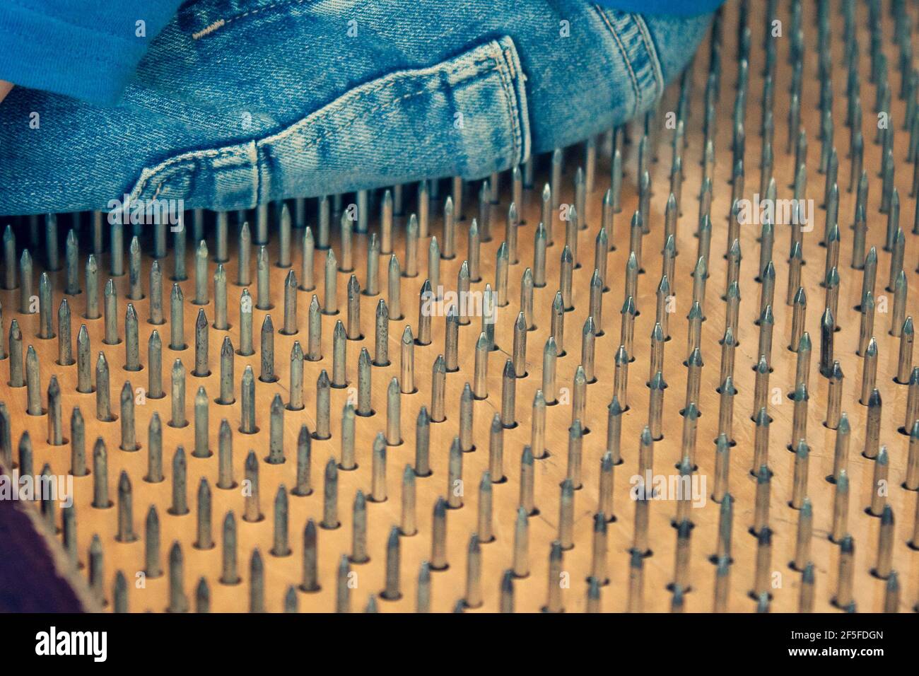 Die Person sitzt auf scharfen Nägeln. Person der entspannenden Bewegung, Stress, extrem Stockfoto