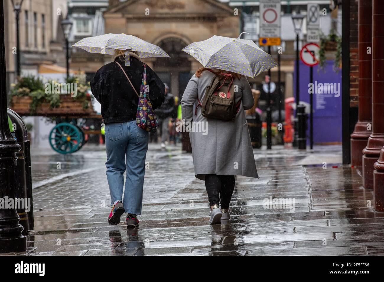 Fußgänger, die sich vor dem Regen schützen, indem sie Regenschirme in den verlassenen Straßen von Londons West End während der Coronavirus-Sperrmaßnahmen in England halten. Stockfoto