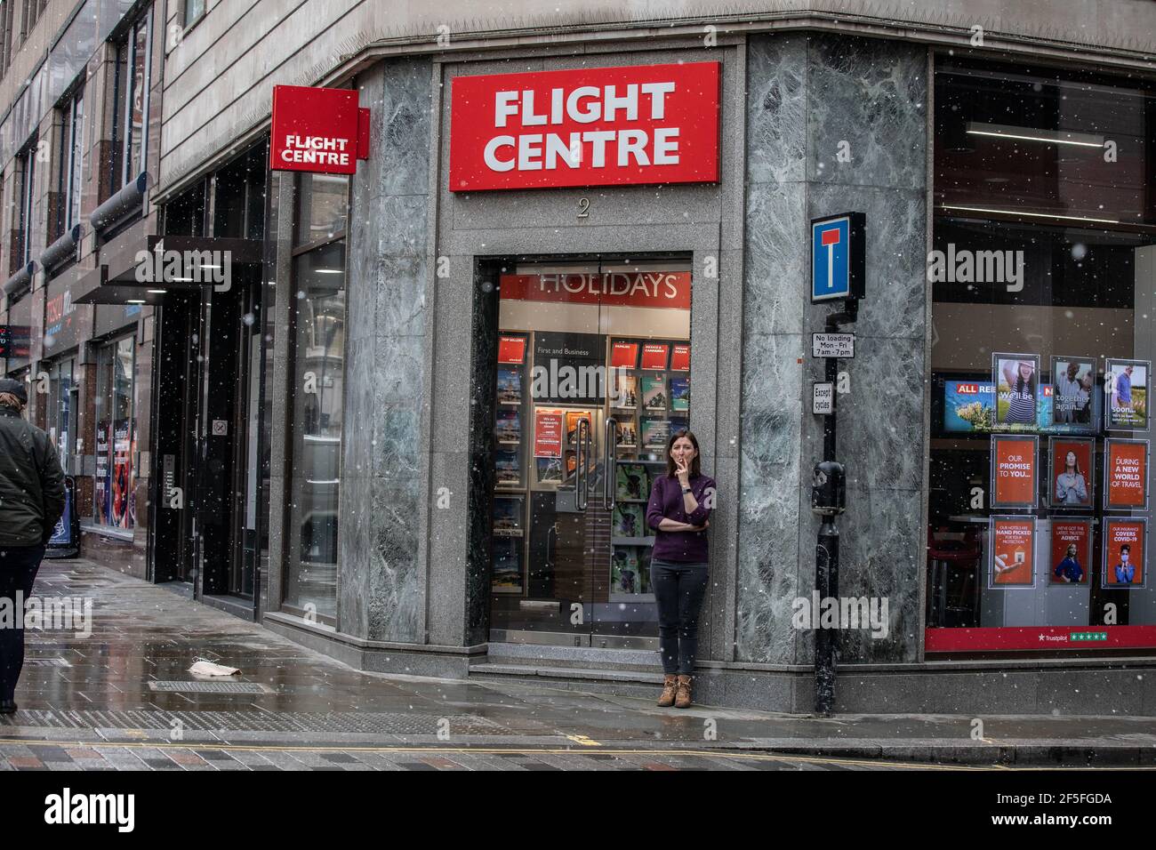 Eine Frau macht eine Pause vor einem leeren Flight Center Reisebüro in der Nähe der London Bridge während der Coronavirus-Sperre im März 2021, London, England, Großbritannien Stockfoto