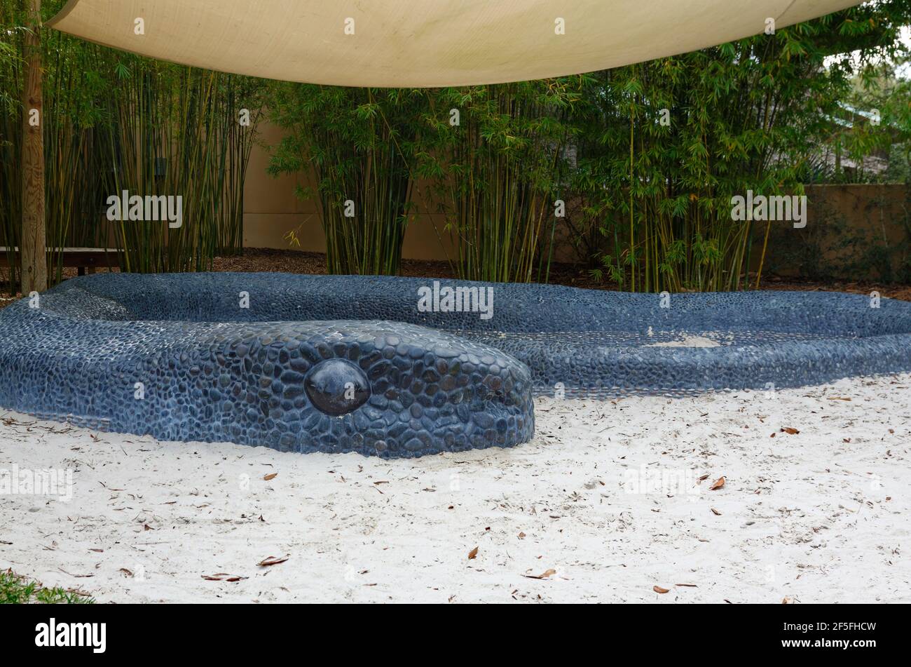 Hängematte Hollow Children's Garden, Indigo Pass, schwarzer Kieselstein Mosaik Schlange Skulptur umgibt Sandkreis, spielen, Entdeckung-basierte Lernen, Spaß, einzigartig Stockfoto
