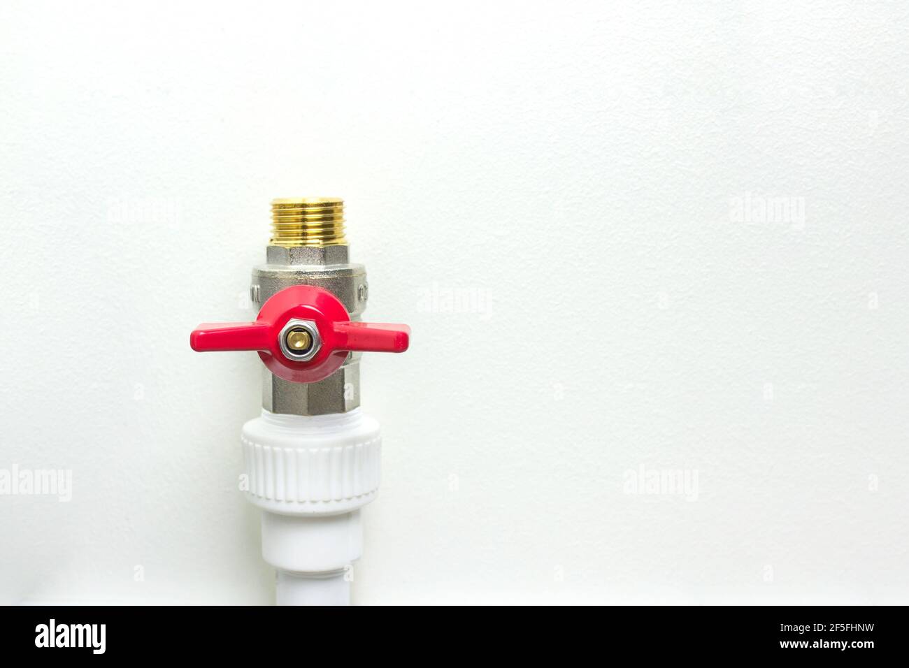 Weißes Polypropylen-Rohr und roter Wasserhahn. Fittings für Wasserleitungen - ein Beispiel für eine Verbindungseinheit bei der Schaffung eines Wasserversorgungssystems aus PVC-Rohren. Stockfoto